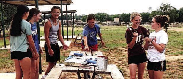PAINTING TABLES - Sundown XC coaches Dakotah Watson and April Berry and team members joined in to paint city picnic tables as a community project. (Sundown ISD photo)