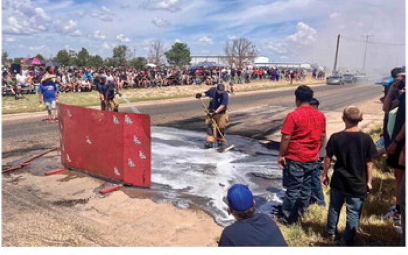 Firefighters Chad Wisdom and Logan Esch cool down the street during the “Thunder on the Plains” burnout competition.