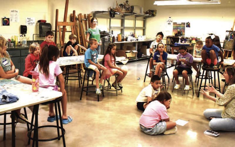 EXPLORE THE ARTS – Participants in the seven and eight-year-old class listening to Emily Wheeler explain how to use oil pastels. This art class was part of the Explore the Arts Camp at SPC last week. (Staff photo by Ada Niederhauser)