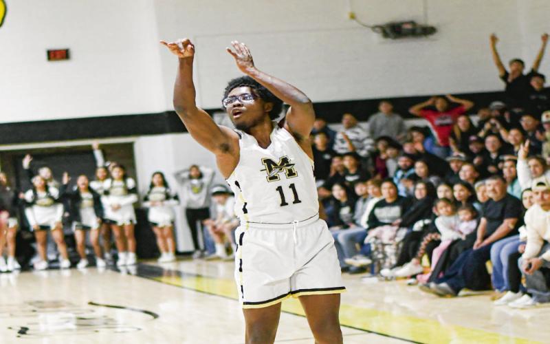 HOLLAND FOR THREE - Morton’s Travion Holland shoots a three-pointer as the crowd anticipates a make behind him during their game against Whiteface this past Tuesday at Morton High School. (Staff photo by Jentezen Smith)