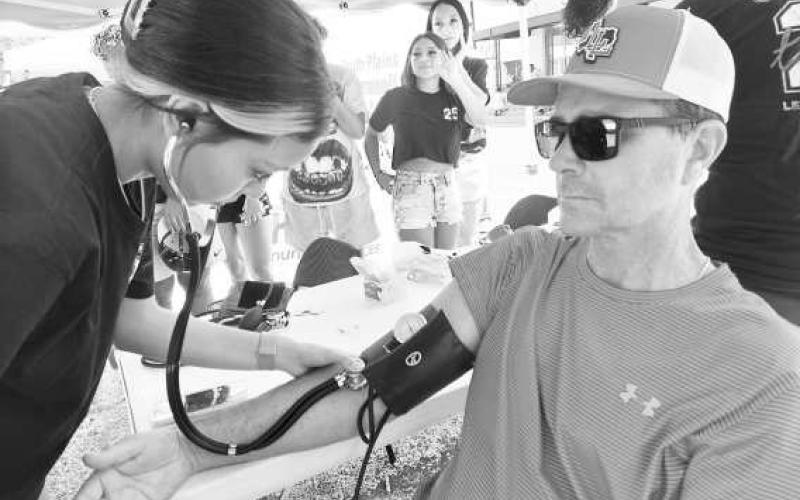 DIAGNOSIS - LHS Patient Care Tech students took advantage of the crowd last weekend at the Sweet HoCo Celebration to practice taking patient vital signs. Students are learning and relearning to be Patient Care Technicians in the class under the direction of Mrs. Joan Sanders. (Photo courtsey of Cristal Isaacks)