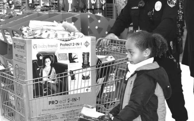 EARLY CHRISTMAS SHOPPING - The Levelland Police Department’s Blue and You hosted its third annual Blue Santa Christmas Event for local community children on Saturday at McDonalds and Wal-Mart. Wal-Mart employees greeted the children with candy canes and hot chocolate. Soon after, local law enforcement officers took the 29 children for the event throughout the store to shop for toys for Christmas. (Staff photo by Emily Campos)