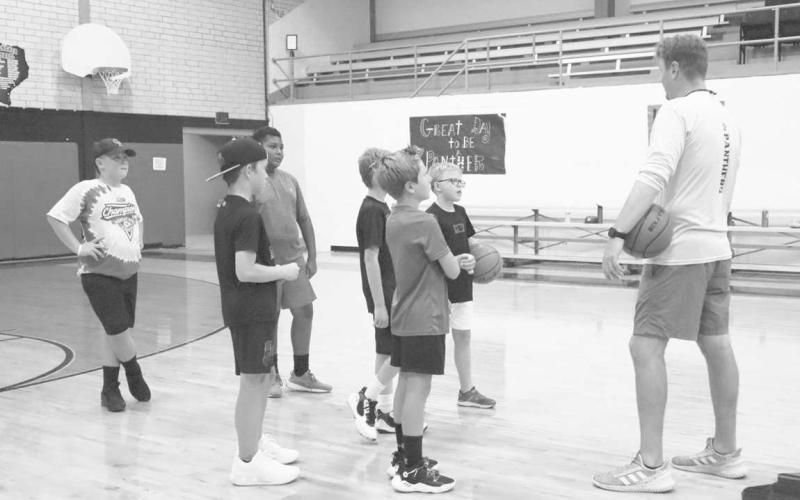 ADAPTIVE - Whitharral Coach Matt White taught the kids attending the Whitharral All-Sports Camp how to dribble, shoot and drive for the basket . Pictured is the first group of kids paying attention to Coach.White as he explained drills. (Staff Photo by Aalijah Soliz)