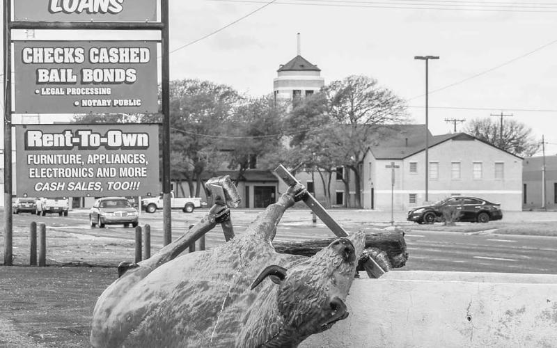 STRONG WINDS – Cleanup crews and volunteers have been working in shifts throughout the day since Wednesday to address the large swaths of debris scattered throughout the community. Pictured is the Personal Loans buffalo statue on Houston Street on its side due to the storms intense wind. (Staff photo by Dom Puente)