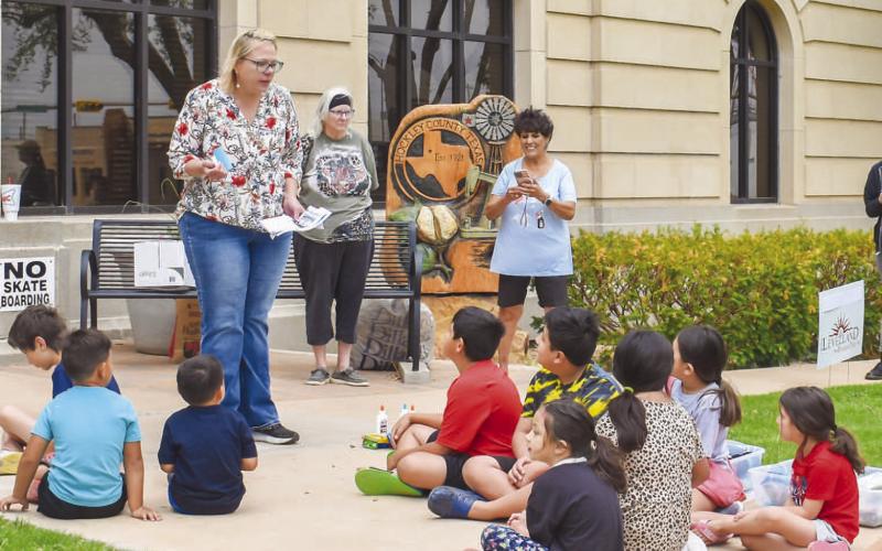 SUMMER READING PROGRAM - Pictured is Kelly Hancock with the Levelland Chamber of Commerce leading the Hockley County Memorial Library’s third event of their Summer Reading Program. The children in attendance learned about recycling by picking up litter from the courthouse lawn and made it into artistic creations. The fourth event is slated for June 26 beginning at 10 a.m. on the courthouse lawn. The theme of the event is “Adventure Quest.” (Staff photo by Emily Campos)