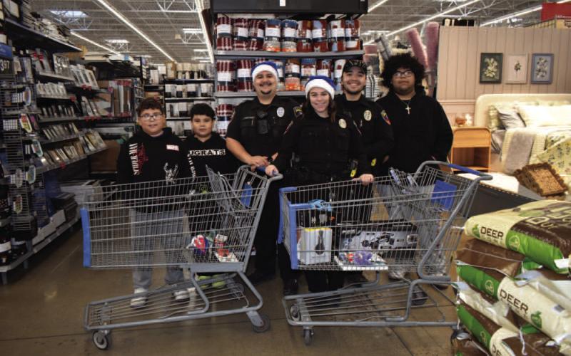 Pictured are Student Resource Officers Rincones and Miranda and Officer Lazcano with their group at the Blue Santa event on Saturday. For the event, police department personnel escorted local children to Walmart where they bought them Christmas gifts. (Staff photo by Ada Niederhauser)