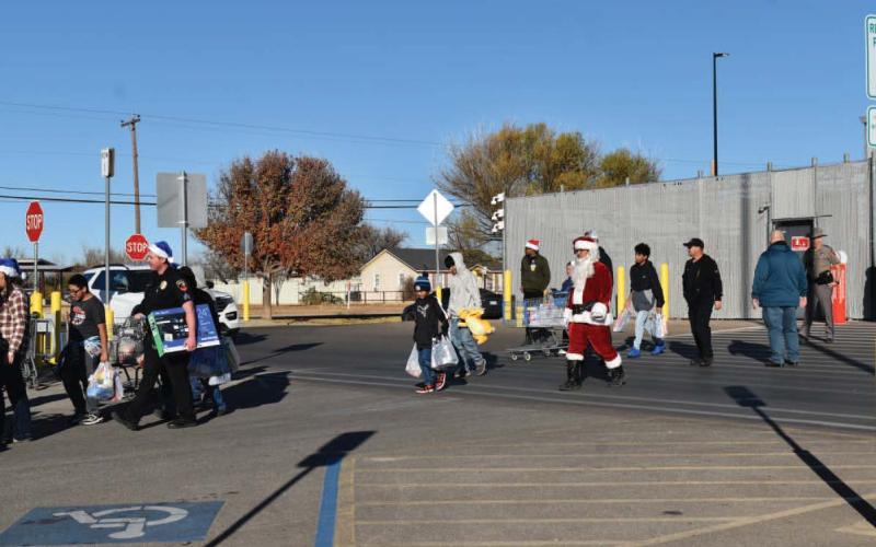 Participants in the Blue Santa event walk out of Walmart after members of the police department bought Christmas gifts for local children on Saturday. The event started at the fire station where children were given a police escort to the store. (Staff photo by Ada Niederhauser)