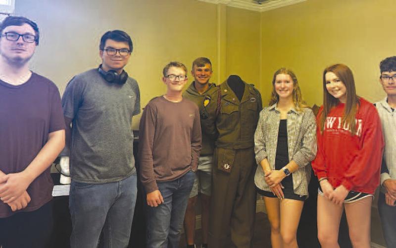 MUSEUM CURATORS - Pictured are junior curators standing with the 82nd Airborne Glider dress uniform on display. The Wallace Theater Pop-up Museum will be open throughout the month of May at the Brasch Mitchell Building located in Levelland. Pictured from left to right are: Corbin Folsom-Edwards, Austin Ojeda, Brady Houston, Nathan Ellis, Georgia McMahan, Elizabeth Hackler and Zachary Lopez. (Photo courtesy of Alycyn Keeling)