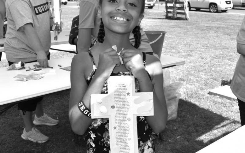 VBS FUN - Oasis Church in Levelland held vacation bible school at the Kaufman Park on Wednesday named Gods Rock-Solid Truth In A World Of Shifting Sand. The group had children participate in games, craft’s, dancing, snacks all structured around Bible school teachings. Pictured is Sophia Taylor with her finished footprint cross craft. (Staff photo by Emily Campos)
