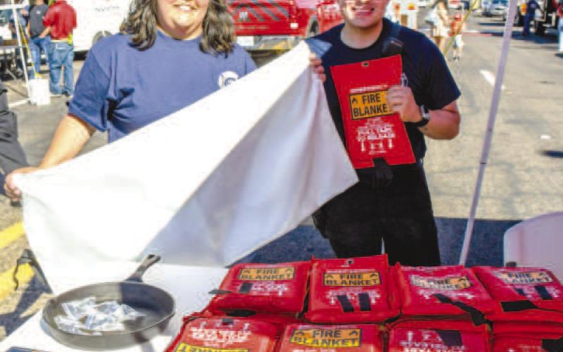 FIRE BLANKETS – Nancy Brewer and Jerry Nino were set up in front of Levelland Fire Department’s Fire Prevention Day during Saturday’s Falling for the Wallace festival. They held up fire blankets that were available to event attendees. (Staff photo by Evin Thomas)