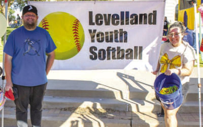 CORNHOLE – Chad and Dellonie Moore posed with a bucket of beanbags under Levelland Youth Softball’s tent at Saturday’s Falling for the Wallace festival in downtown Levelland. Eventgoers were able to play a game of cornhole at the organization’s tent, which was set up alongside other games and live music on Avenue H. (Staff photo by Evin Thomas)