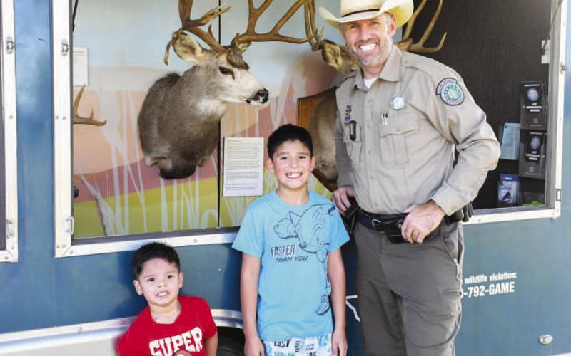 TEXAS GAME WARDEN – Texas Game Warden Drew Spencer smiled with Luka and Noah after showing them around the Texas Game Warden car at Tuesday’s Texas Night Out in Levelland. (Staff photo by Evin Thomas)