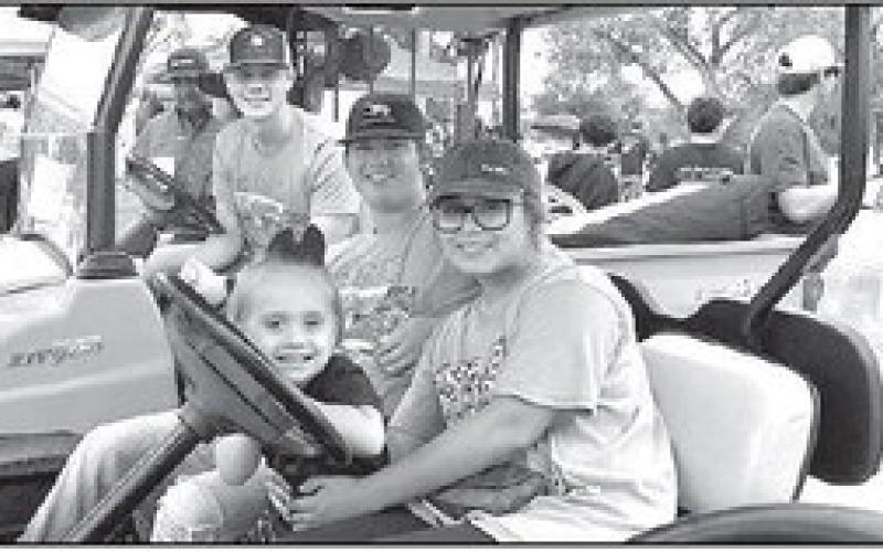 FAMILY FUN IN THE RAIN– Cliffton Turner’s grandchildren Kennedy Newsom, Mason Newsom and Lynelle Newsom and his great-granddaughter, Braylin Newsom, 2, were all enjoying the Thunder on the Plains Classic Car Show Saturday in the City Park. Carol and Cliffton have six grandchildren and one greatgranddaughter. (Staff Photo)