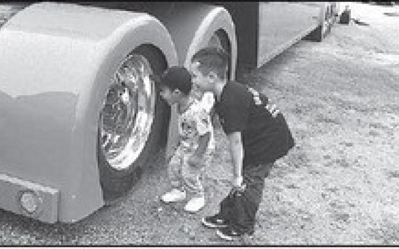 BIGWHEELSPOPPIN’-- Kade Castro, 2, and Axel Wheeler, 5, were amazed of their reflection in the giant wheel of a trailer at the Thunder on the Plains Classic Car Show. Kade is the son of Dom and Mercedes Castro and Axel is the son of Bryce and Sasha Wheeler, all of Levelland. (Staff Photo)