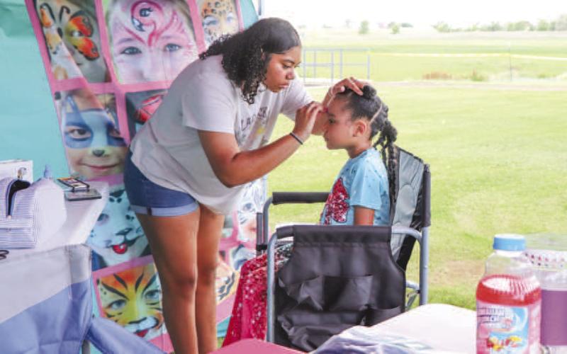 FACE PAINTING - Pictured is Trinty Wafer painting Brynleigh Golightly’s face during the annual Juneteenth Celebration. Wafer had a facepainting booth where she painted kids faces to resemble lions, butterflies and other animals. (Staff photo by Essence Childers).