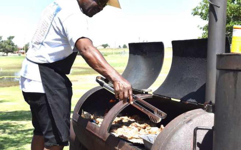 CHECKING THE MEAT – Willie Jones is pictured grilling meat for the annual Juneteenth celebration. The meal is provided by donations from community members and businesses. (Staff photo)