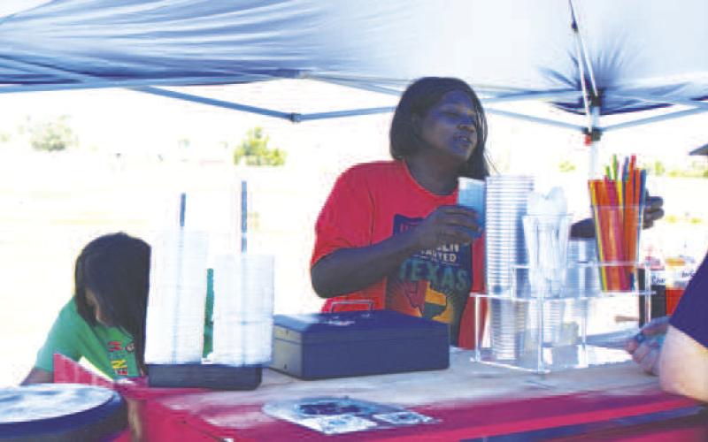 REFRESHING SNACK- Tina Williams along with her daughter Blakely Lockett are pictured serving Ice Water to residents at the annual Juneteenth celebration held at L.G. Griffin Park this past weekend. (Staff photo)