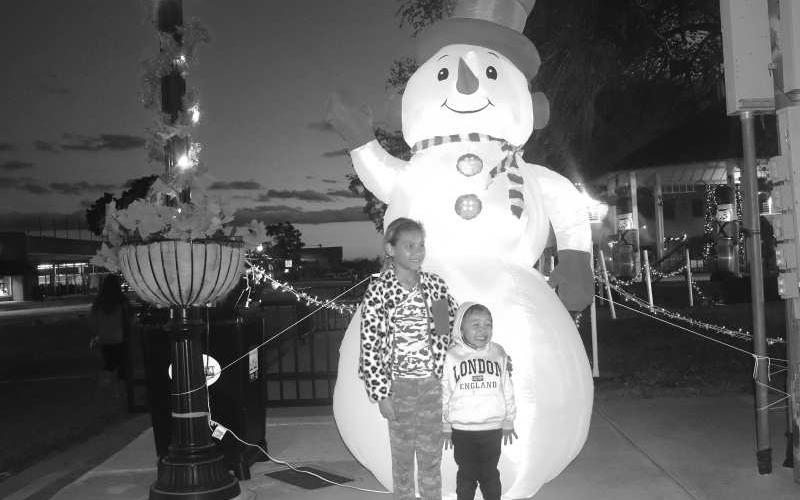 FROSTY- As the Parade of Lights was on its way Thursday evening to the court house square Laezeah and brother Remy Braithwaite are pictured with Frosty the snow man. (Staff photo by Emily Campos)
