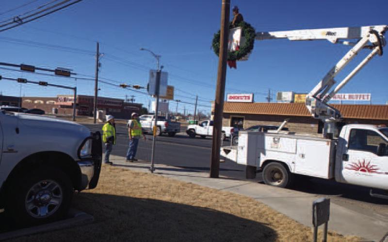 Pictured are workers with the Street Department hanging Christmas decorations back up that were blown down by wind on College Ave. this past Monday. (Staff photo Karin Riddle)