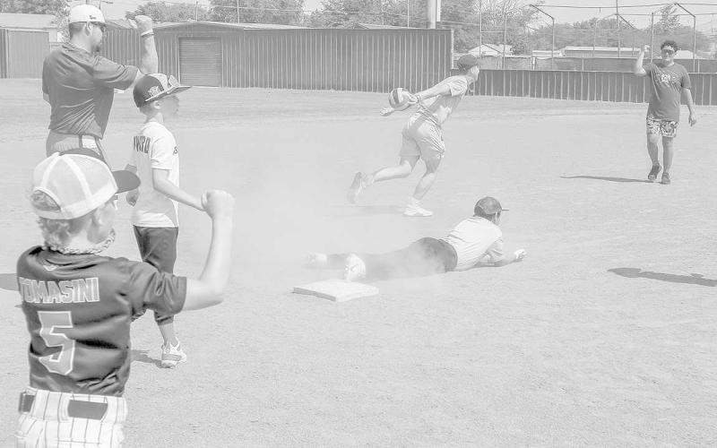 OUT- Lobo camp took place June 28-30 at Levelland High School. The camp was hosted by head coach Chris Portwood and several formal players. Pictured is coach Portwood getting help from campers on an out call at second. (Staff Photo by Aalijah Soliz)