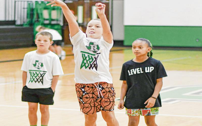 MID-RANGE GAME - Eagle camper Brant Smith shows off his mid-range game while campmates Gus Smith and Aaniya Acevedo watch this past Tuesday at the Ropes High School gym. (Staff photo by Jentezen Smith)