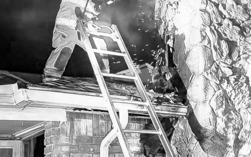 TAKING OUTTHE FLAME - The Levelland Fire Department (LFD) responded to the 1800 block of Houston Street Monday night after receiving a report of a structure fire. Upon arrival, fire was exposed through the roof on the side of the structure. Pictured is an LFD firefighter knocking out a portion of the chimney to expose the flames. (Photo courtesy of the LFD)