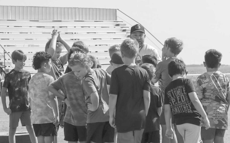 ALL-SPORTS CAMP - Whitharral Head Football Coach Jeremy Holt gathered the kids around him to talk about what they were going to do on the first day of the camp along with Coach Matt White and Brett Berger. (Staff photo by Aalijah Soliz)
