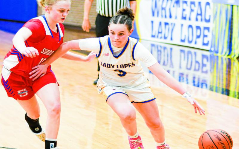 DRIBBLE DRIVE - Whiteface’s Kambry Sanders dribble drives past Sundown’s Kaytlin Clausen during their district game this past Tuesday night at Whiteface High School. (Staff photo by Jentezen Smith)