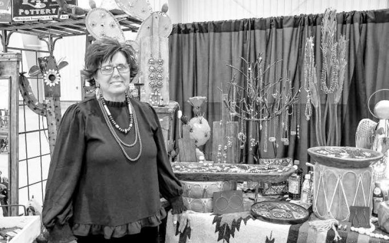 LATI’S POTTERY PIG – Melanie Burnett of Lati’s Pottery Pig smiled next to her necklaces and other jewelry she had displayed for the Clovis Horse Sale trade show Nov. 23 in Levelland. (Staff photo by Evin Thomas).