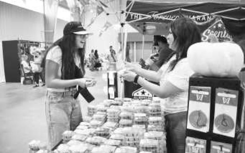 FUN WITH CANDLES - Pictured are Emma Ayers and Angie Garza smelling candles at the Yucca Blossom Trade Day event at the Mallet Event center on Saturday. At the event, vendors had the opportunity to talk with customers while advertising their business and possibly having some sales. (Staff photo by Ada Niederhauser)