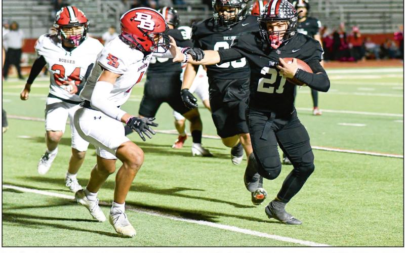 STIFF ARM ‘EM - Levelland junior running back Jake Potter rushes the football and stiff arms a Borger defender during a football game this past Friday night at Lobo Stadium. Potter would rush for two touchdowns in the Lobos 46-12 win. (Staff photo by Jentezen Smith)