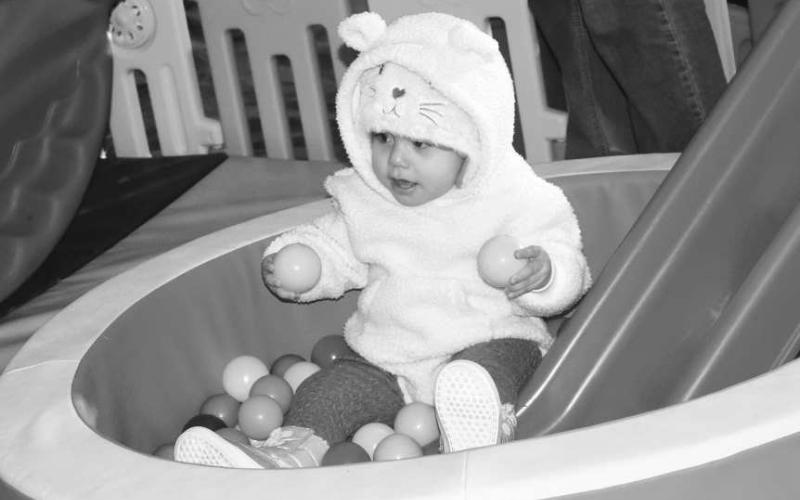 CUTENESS OVERLOAD- As the Event Festival of Lights begin with many activities on the square on Thursday evening little Victoria De La Cerna is caught playing in one of the bounce houses.(Staff photo by Emily Campos)