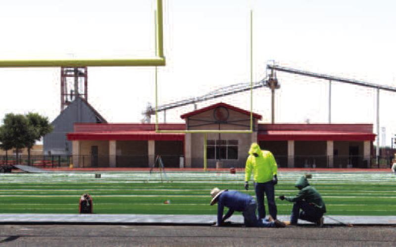 EDGES SECURED - Contractors secure the edge of the new artificial turf field at Levelland High School. (Staff photo by Trinity Bourdeaux)