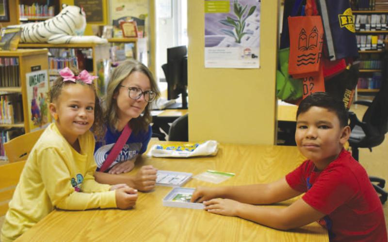 SUMMER READING – Pictured are Kylea, Rebekah and Bentley playing mini Sorry at the library on Wednesday. The week’s summer reading activity consisted of board games inside where there was air conditioning. (Staff photo by Ada Niederhauser)