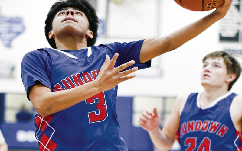 FANCY FINISH - Sundown Roughneck Athan Peralez scores a basket after pulling off a fancy move to evade Smyer defenders this past Friday night during their game at Smyer High School. (Staff photo by Jentezen Smith)