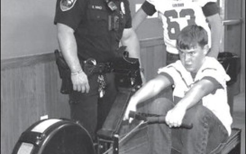 One of the booths at the Exploration Event at the Mallet Event Center on Thursday was Officer R. Nino teaching and timing Cody Holdman one of the students participation in the event as he tried to break a record on a Concept 2 training equipment while Aiden Brinklow cheered him on. (Staff photo by Emily Campos)