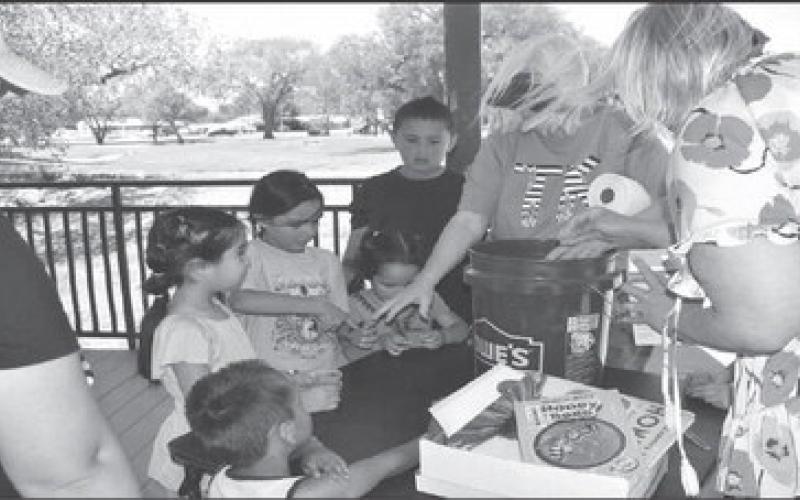 PLANTING - The Levelland Chamber of Commerce celebrated Earth Day with a few activities Tuesday afternoon at Lobo Lake. Kelly Hancock and Donna Wheeler helped children with planting seeds in small cups for them to take home and plant at their home.(Staff photo by Emily Campos)