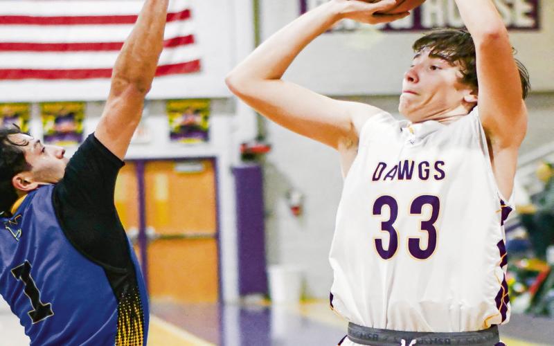 CARLOCK CONTESTED SHOT - Anton Bulldog Caleb Carlock shoots a three-pointer with a Wellman Union defender right in his face during their game this past Friday night at Anton High School. (Staff photo by Jentezen Smith)