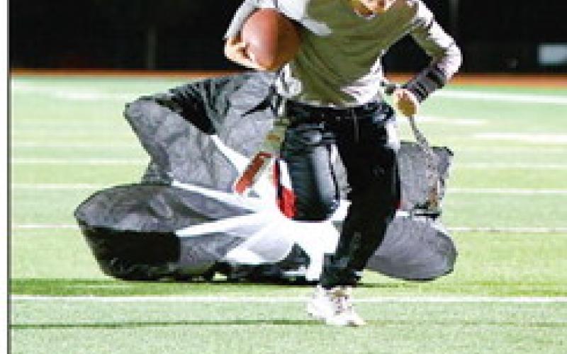 PARACHUTE RUN - Kyler Dent carries the football while dragging a resistance training parachute with him at Lobo Stadium this past Monday. Dent is a part of the 8u Levelland Lobos flag football team that will be competing at the Star in Frisco for an NFL Regional Flag Football tournament over the weekend. (Staff photo by Jentezen Smith)
