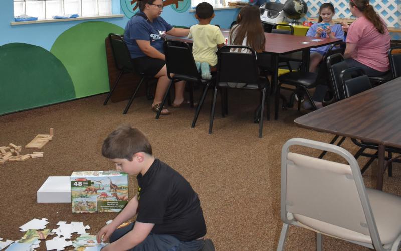 SOMETHING TO DO - Pictured are participants in the summer reading activ-ity at the library on Wednesday. They enjoyed many activities like board games, Jenga and puzzles. (Staff photo by Ada Niederhauser)