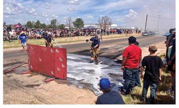 Firefighters Chad Wisdom and Logan Esch cool down the street during the “Thunder on the Plains” burnout competition.