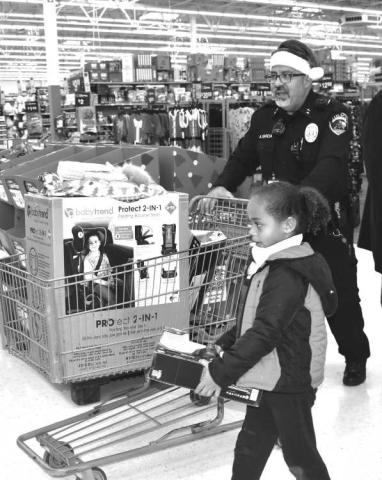 EARLY CHRISTMAS SHOPPING - The Levelland Police Department’s Blue and You hosted its third annual Blue Santa Christmas Event for local community children on Saturday at McDonalds and Wal-Mart. Wal-Mart employees greeted the children with candy canes and hot chocolate. Soon after, local law enforcement officers took the 29 children for the event throughout the store to shop for toys for Christmas. (Staff photo by Emily Campos)