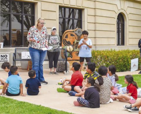 SUMMER READING PROGRAM - Pictured is Kelly Hancock with the Levelland Chamber of Commerce leading the Hockley County Memorial Library’s third event of their Summer Reading Program. The children in attendance learned about recycling by picking up litter from the courthouse lawn and made it into artistic creations. The fourth event is slated for June 26 beginning at 10 a.m. on the courthouse lawn. The theme of the event is “Adventure Quest.” (Staff photo by Emily Campos)