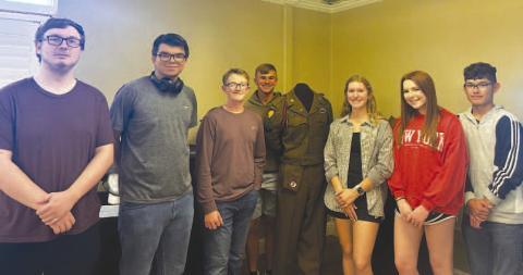 MUSEUM CURATORS - Pictured are junior curators standing with the 82nd Airborne Glider dress uniform on display. The Wallace Theater Pop-up Museum will be open throughout the month of May at the Brasch Mitchell Building located in Levelland. Pictured from left to right are: Corbin Folsom-Edwards, Austin Ojeda, Brady Houston, Nathan Ellis, Georgia McMahan, Elizabeth Hackler and Zachary Lopez. (Photo courtesy of Alycyn Keeling)