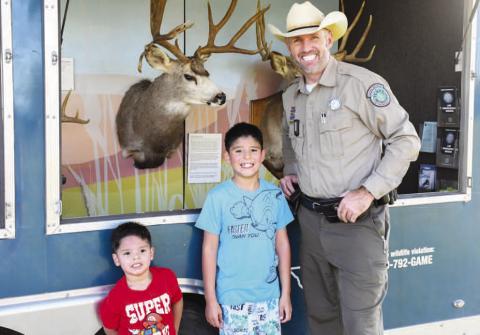 TEXAS GAME WARDEN – Texas Game Warden Drew Spencer smiled with Luka and Noah after showing them around the Texas Game Warden car at Tuesday’s Texas Night Out in Levelland. (Staff photo by Evin Thomas)