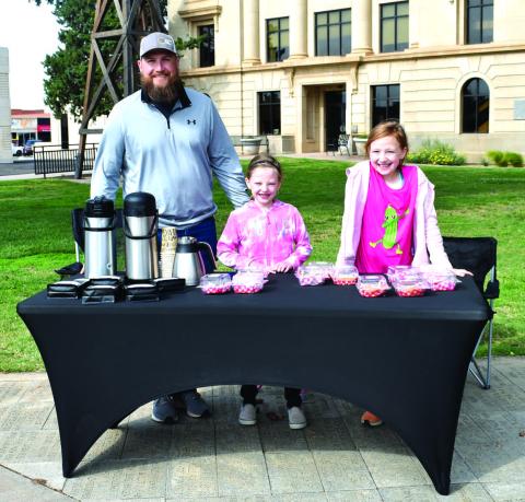 FAMILY FUN - Jacob Tucker and his daughters participated in the Lemonade Day event held by Levelland Main Street on Saturday down on the square. Pictured is Jacob Tucker selling his famous coffee, Lilly Tucker’s famous pickle bread and jam and Charley Tucker’s famous cookies. (Staff photo by Emily Campos)