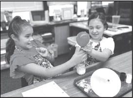 STATE OF MATTER - The fourth grade students in Mrs. Clara Sander’s Science classes at the Capitol Elementary school are learning about the states of matter. In photo Sofia Lopez and Keelyn Zamora are enjoying Hands-on-learning in the lab of what happens when matter are mixed together (photo submitted by Cristal Isaacks)