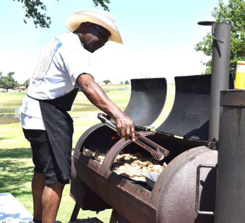 CHECKING THE MEAT – Willie Jones is pictured grilling meat for the annual Juneteenth celebration. The meal is provided by donations from community members and businesses. (Staff photo)