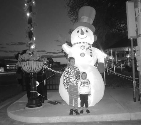 FROSTY- As the Parade of Lights was on its way Thursday evening to the court house square Laezeah and brother Remy Braithwaite are pictured with Frosty the snow man. (Staff photo by Emily Campos)
