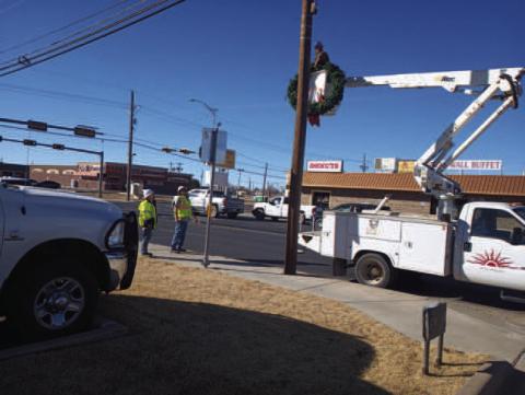 Pictured are workers with the Street Department hanging Christmas decorations back up that were blown down by wind on College Ave. this past Monday. (Staff photo Karin Riddle)